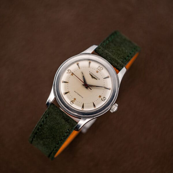 Complete vintage Longines 6280-5 overhead on its forest green suede strap with orange leather lining
