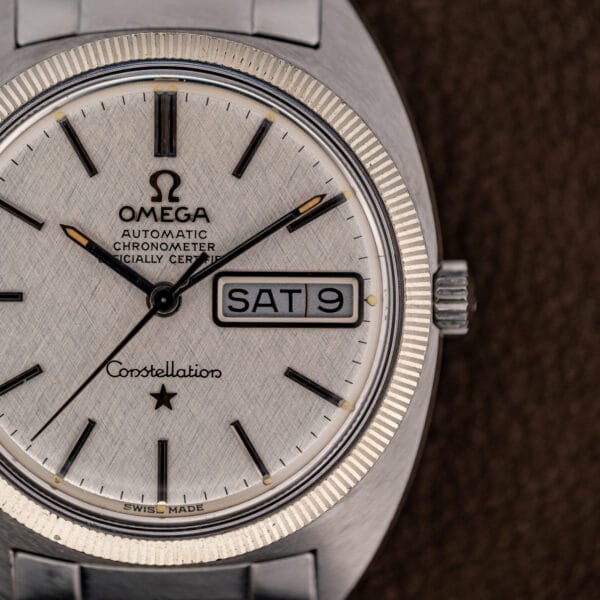 Vintage Omega Constellation dial macro showing AUTOMATIC CHRONOMETER OFFICIALLY CERTIFIED text above the framed day and date window