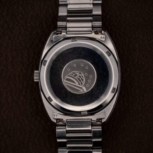 Omega Constellation caseback observatory medallion, cupola beneath eight stars, on polished stainless steel with honest wrist wear