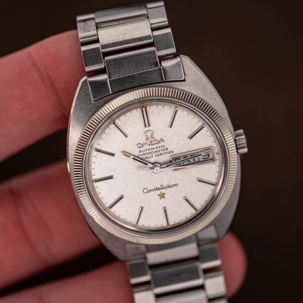 Close in hand view of the Omega Constellation linen dial, gilt star and sharply fluted bezel