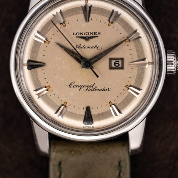 Angled Conquest Calendar dial macro with twelve applied faceted markers and tan-aged lume plots intact