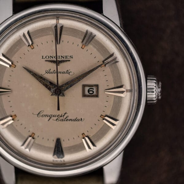 Extreme close view of the Longines 9004-3 dial and fluted crown with scattered age speckling