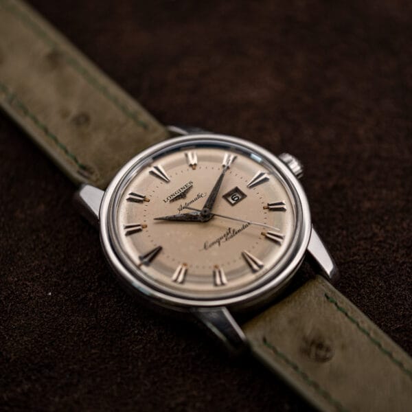Raking light across the Conquest Calendar dial reveals warm amber toning through the left half