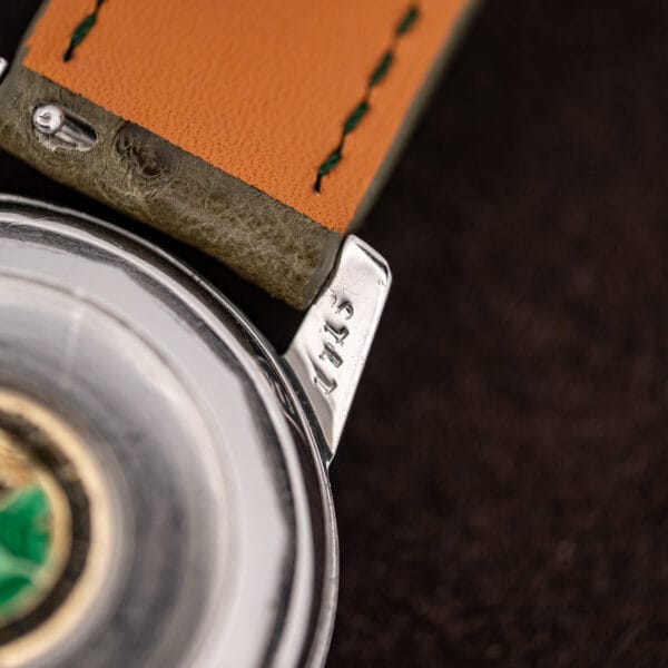 Macro of the lug underside and strap end showing shallow stamped characters and orange leather backing