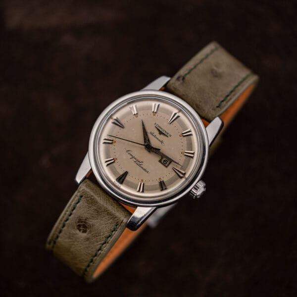 Overhead view of the Longines Conquest Calendar 9004-3 on its olive ostrich strap against brown suede