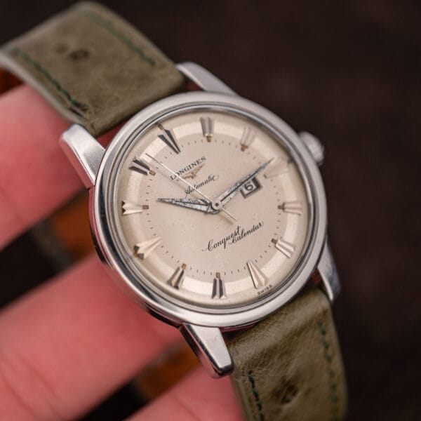 Held in hand, the Conquest Calendar 9004-3 shows its dial scale, domed crystal and applied faceted markers