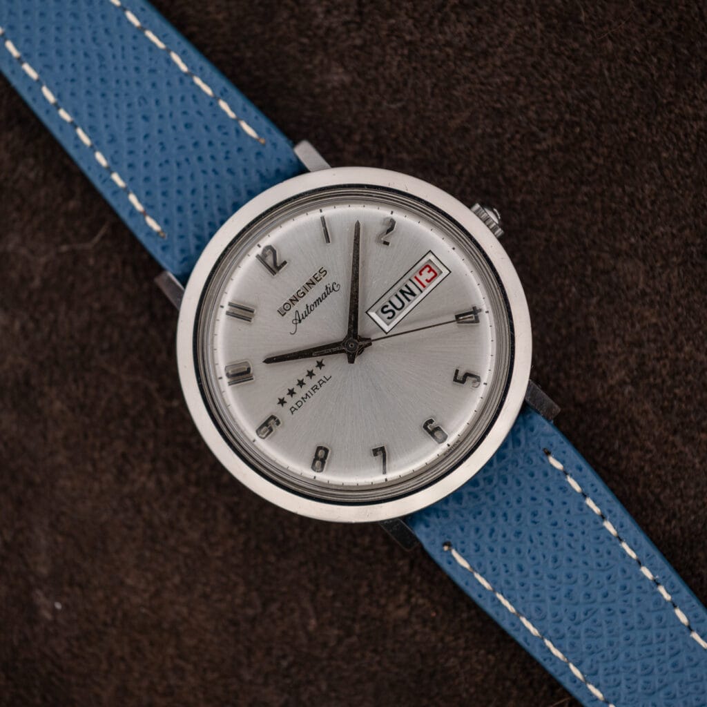 Longines Admiral automatic with silver sunburst dial, five-star marking and day date window on blue leather