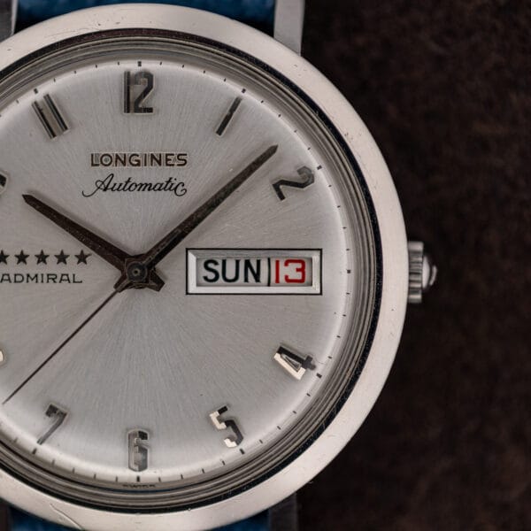 Macro of the Longines Admiral dial showing applied LONGINES lettering, Automatic script and chrome framed day date aperture