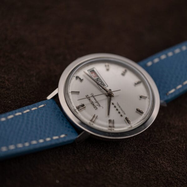 Inverted angle of the Longines Admiral as light crosses the crystal, highlighting surface wear above the clean silver dial