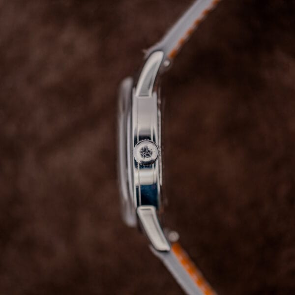 Star-signed Zenith winding crown in profile against the polished mid-case band of the stainless steel case