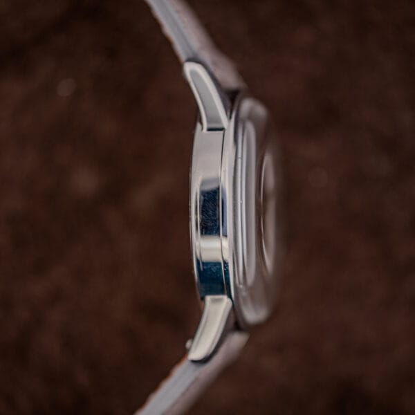 Side profile of a vintage Zenith showing slim case thickness, snap caseback seam and polished downturned lugs