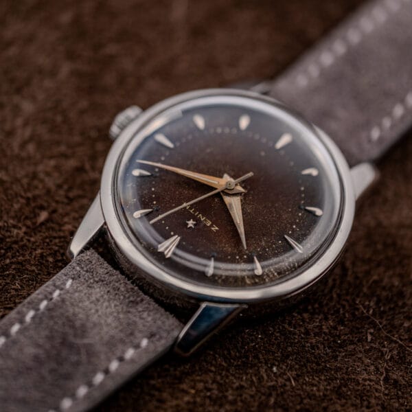 Close angle on the Zenith dial edge showing near-black outer chapter, aged lume plots and domed crystal
