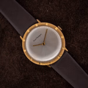Girard-Perregaux silver sunburst dial, two gold-toned hands, and a textured bezel with twelve polished notches, shown on suede