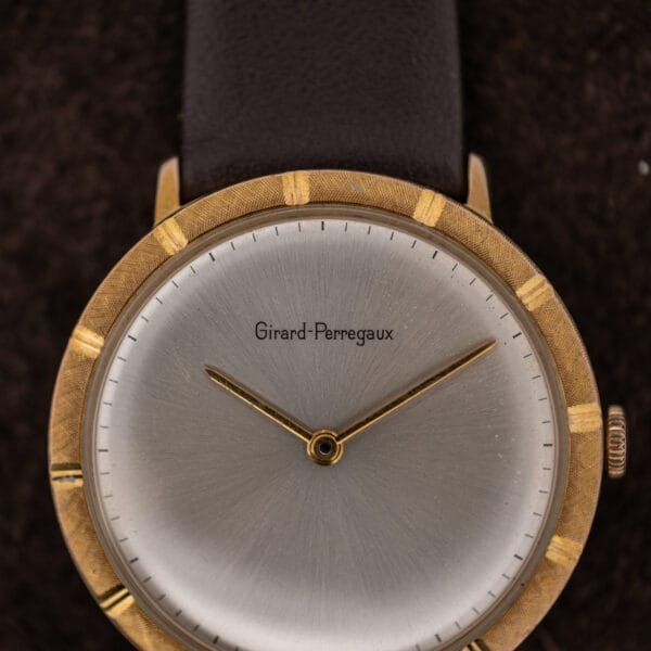 Macro of the Girard-Perregaux dial signature, printed baton minute track, and radial sunburst brushing under a domed crystal
