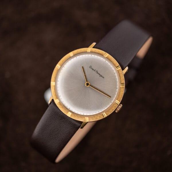 Girard-Perregaux on its brown leather strap, two gold hands over the silver sunburst field and printed minute track