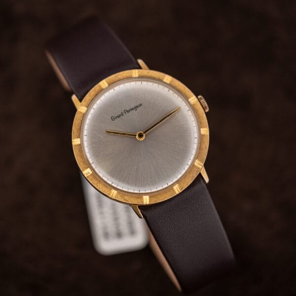 Tilted view of the Girard-Perregaux showing crystal wear across the lower dial and brightened high points on the bezel