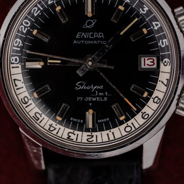 Dial macro of a vintage Enicar Sherpa Jet showing the Saturn logo, applied luminous batons and red date