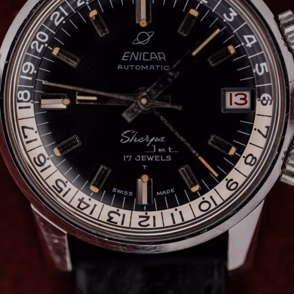 Dial macro of a vintage Enicar Sherpa Jet showing the Saturn logo, applied luminous batons and red date