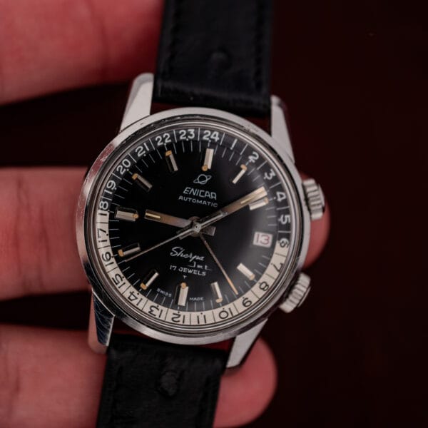Close in-hand view of the Enicar Sherpa Jet black dial, date window and honest case wear