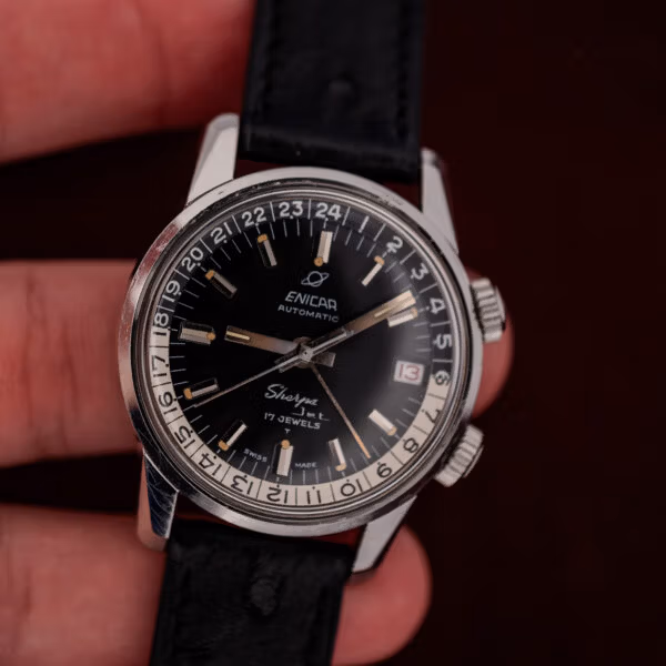 Close in-hand view of the Enicar Sherpa Jet black dial, date window and honest case wear