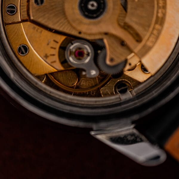 Boxed AR caliber stamp on the gilt mainplate of the Enicar automatic movement under magnification