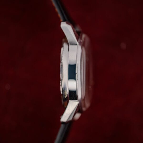 Plain nine o'clock flank of the Enicar Sherpa Jet case with stepped bezel and angular tapering lugs