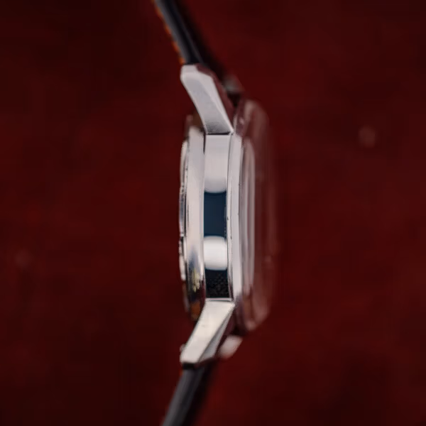 Plain nine o'clock flank of the Enicar Sherpa Jet case with stepped bezel and angular tapering lugs
