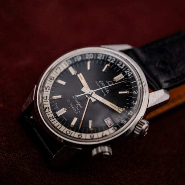 Vintage Enicar Sherpa Jet from above left showing black dial, 24-hour bezel, twin crowns and polished lugs