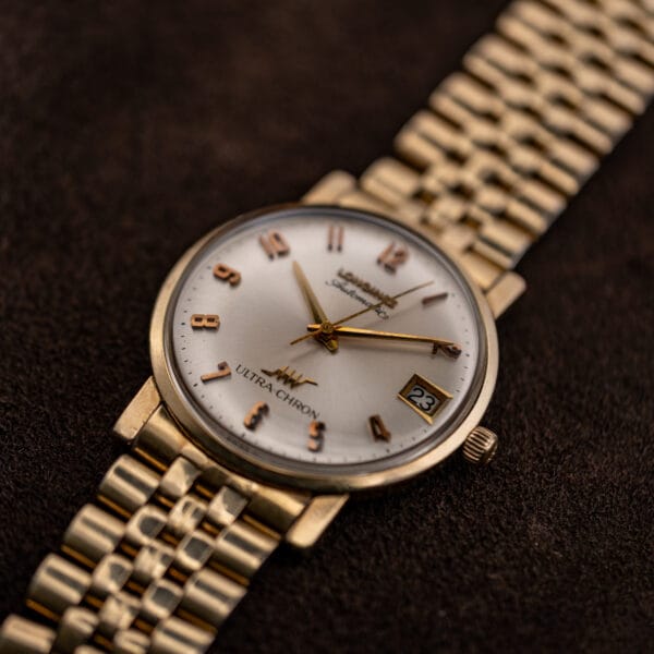 Angled view of the Longines Ultra-Chron showing its slim gold filled case, downturned lugs and fluted crown