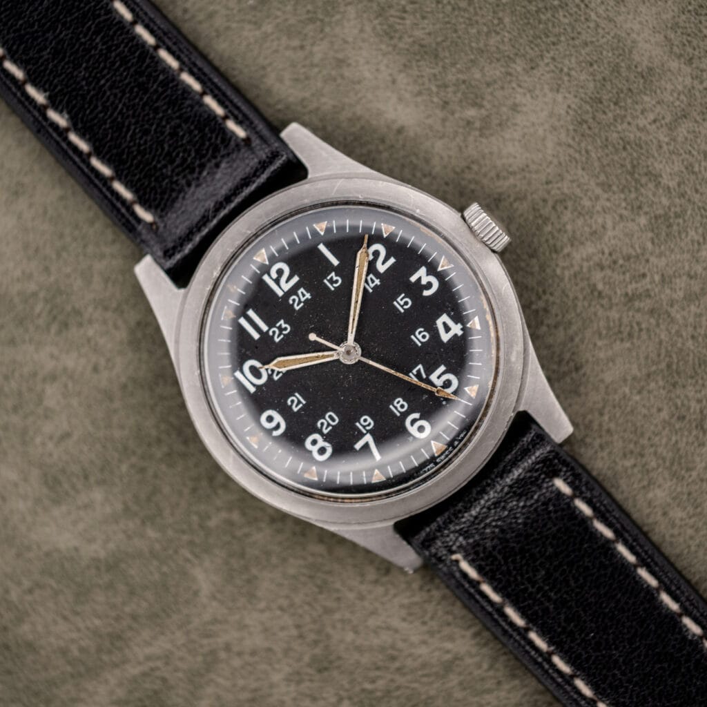 Benrus GG-W-113 sterile black dial with 12-hour and 24-hour numerals, aged tan lume and black leather strap