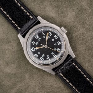 Benrus GG-W-113 sterile black dial with 12-hour and 24-hour numerals, aged tan lume and black leather strap