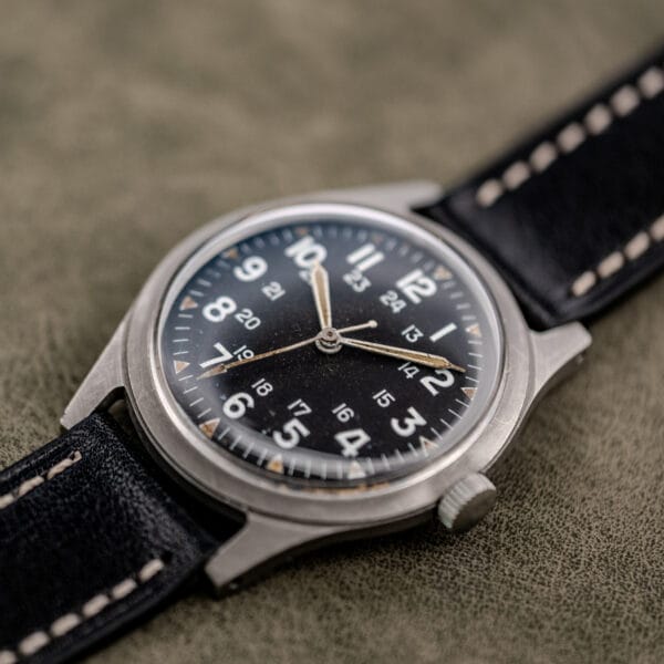 Angled product shot of the Benrus GG-W-113 showing domed acrylic crystal, matte case flank and unsigned fluted crown
