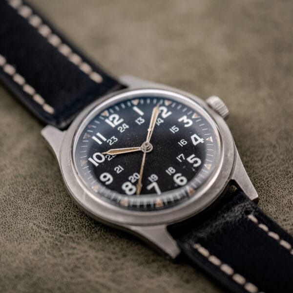 Low angle view of the Benrus GG-W-113 pilot spec dial, white military numerals over matte black with chapter ring patina