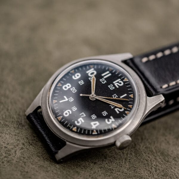 Benrus GG-W-113 three quarter view with dual 12 and 24 hour tracks, aged lume plots and bead-blasted grey case