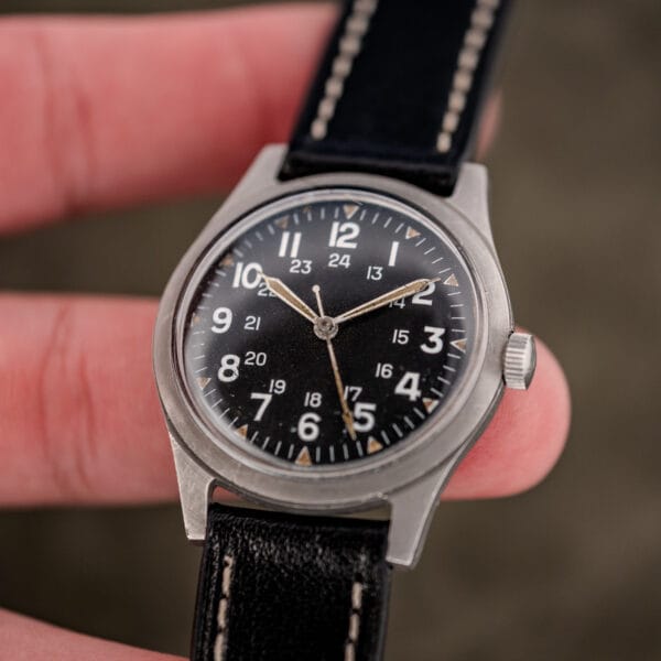 Close in hand photo of the Benrus GG-W-113 dial, aged orange tan lume triangles and unsigned coin edge crown