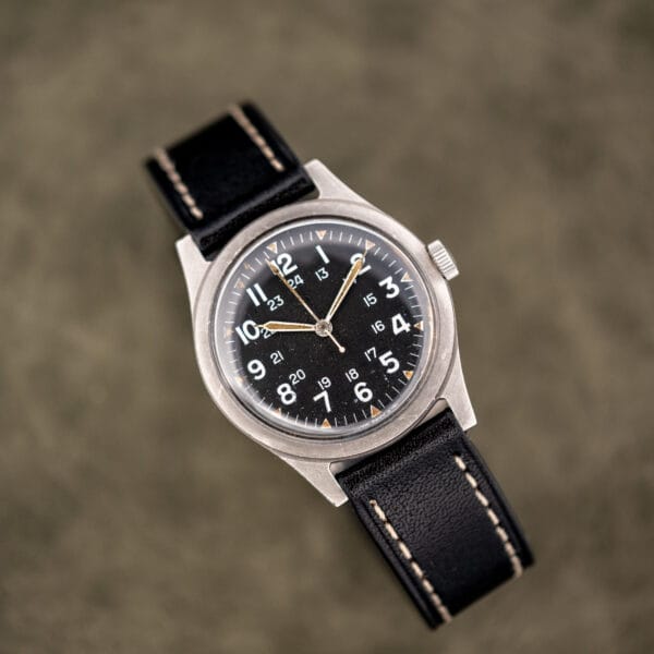 Benrus GG-W-113 Vietnam era pilot spec photographed overhead, matte black dial, worn steel case and leather strap