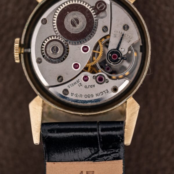 Elgin 680 movement macro showing ADJ'D and 21 JEWELS stamps, balance wheel and S-F regulator index