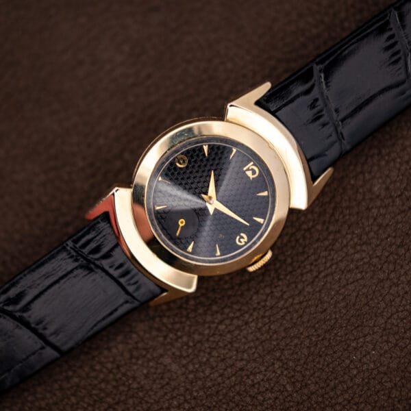 Vintage Lord Elgin watch at an angle, black textured dial, fluted crown and gold filled bezel