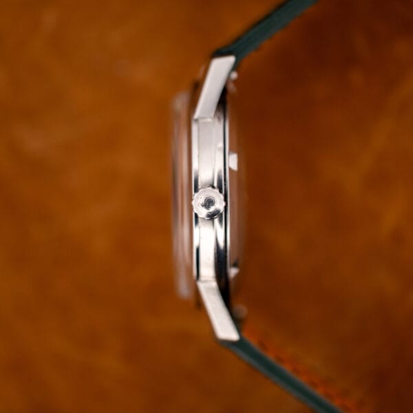 Side profile of Omega 14773-1 stainless steel case showing worn unsigned crown and straight polished lugs