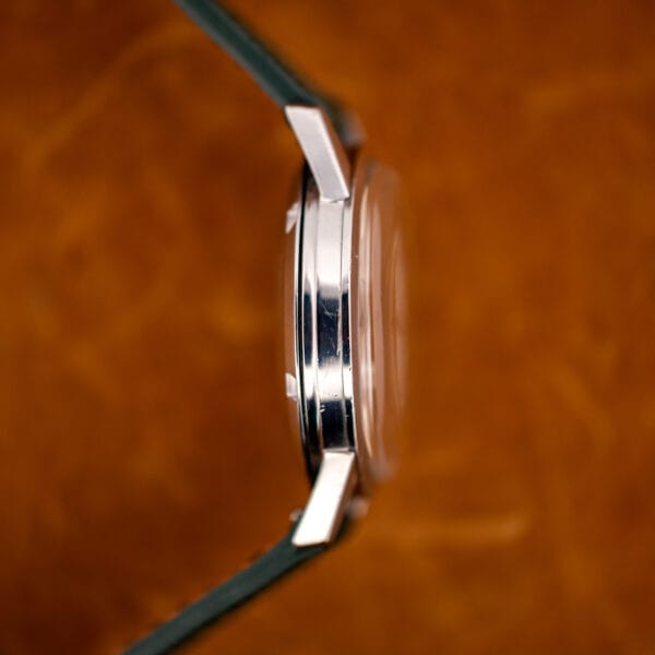 Omega 14773-1 case flank with high domed acrylic crystal standing proud of the smooth steel bezel