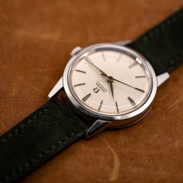 Omega 14773-1 photographed at an angle, applied hour markers catching light across the aged white dial