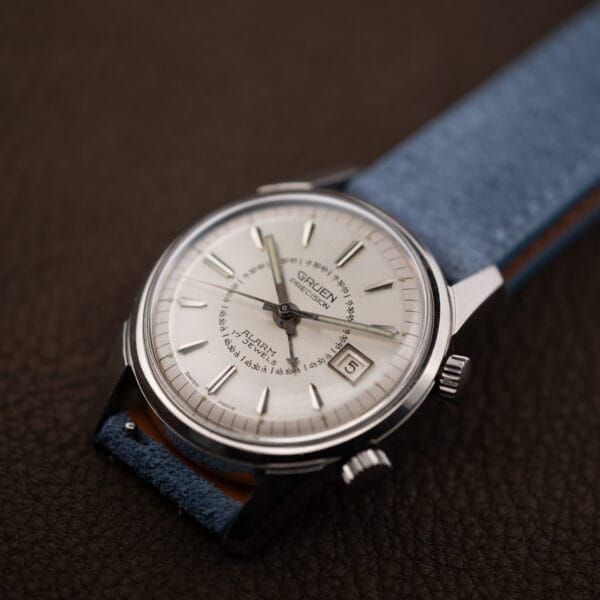 Vintage Gruen Precision Alarm on blue suede, acrylic crystal and sharply faceted stainless lugs in profile