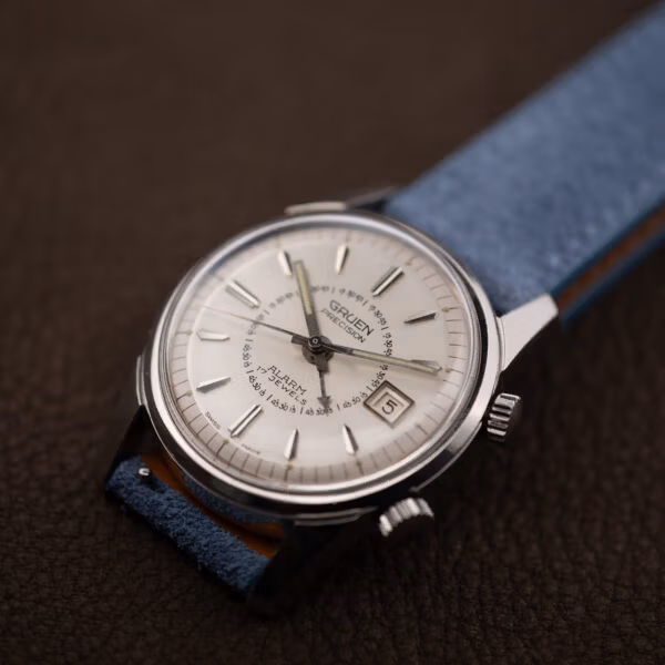 Vintage Gruen Precision Alarm on blue suede, acrylic crystal and sharply faceted stainless lugs in profile