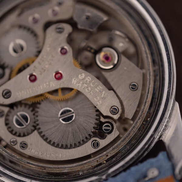 Macro of the Gruen alarm movement stamped GRUEN WATCH Co and UNADJUSTED beside jeweled bearings