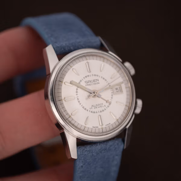 Angled view of the vintage Gruen Precision Alarm, twin crowns, blue suede strap and date window