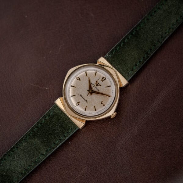 Vintage Wittnauer automatic watch photographed on the diagonal, gold filled hooded lugs and green suede strap