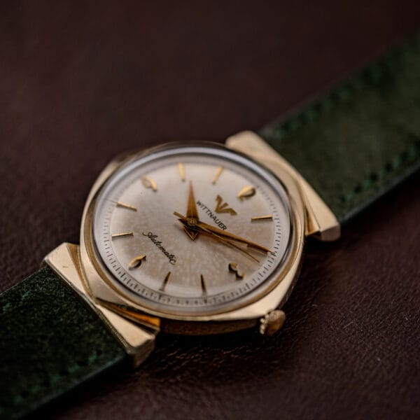 Dial of the 2598-1 at an angle, mottled silver surface and gold dauphine hands under a scratched crystal