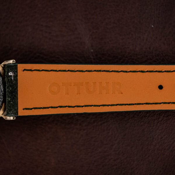 Underside of the forest green Italian suede strap, tan backing with green edge stitching, embossed OTTUHR
