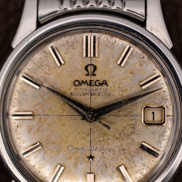 Omega Constellation dial macro showing crosshair lines, applied baton markers and printed AUTOMATIC CHRONOMETER above the Constellation script