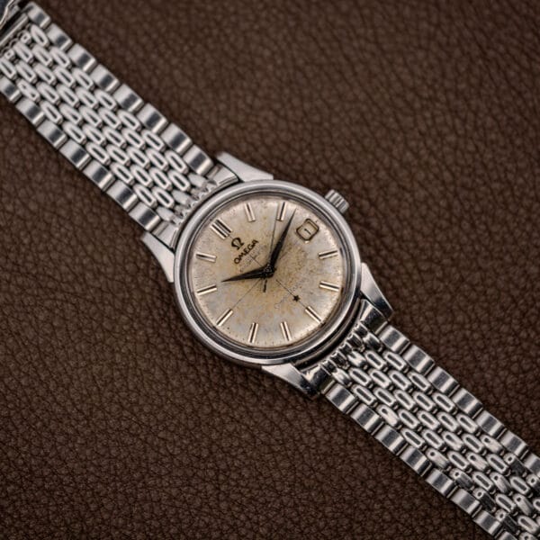 Vintage Omega Constellation 14393 watch on a steel bracelet photographed against brown textured leather